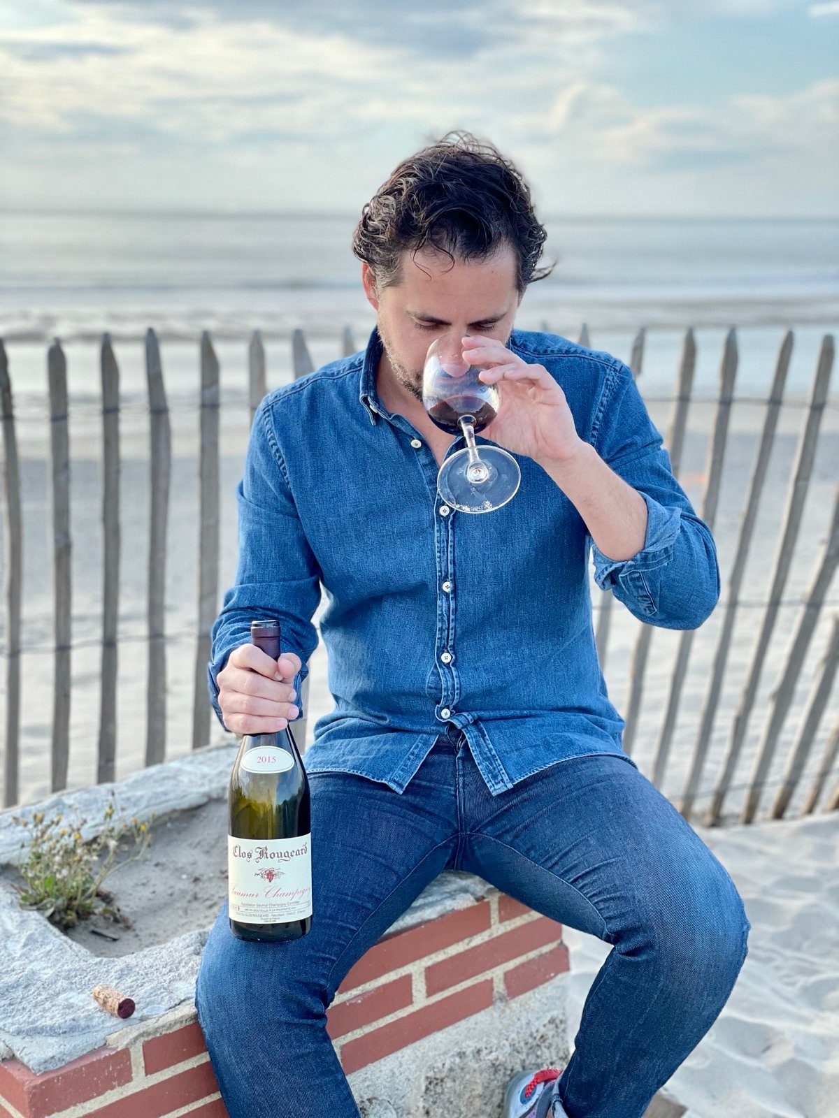 Gildas Reynaud tasting a glass of wine by the water
