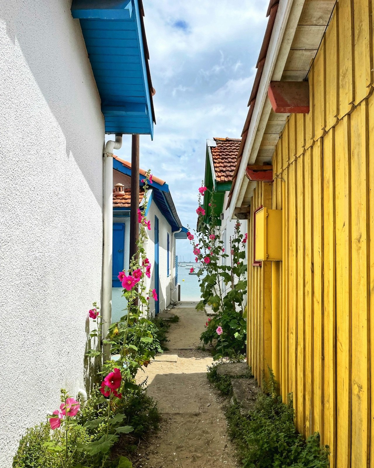 A narrow lane between colourful wooden cabins in a Cap Ferret oyster village