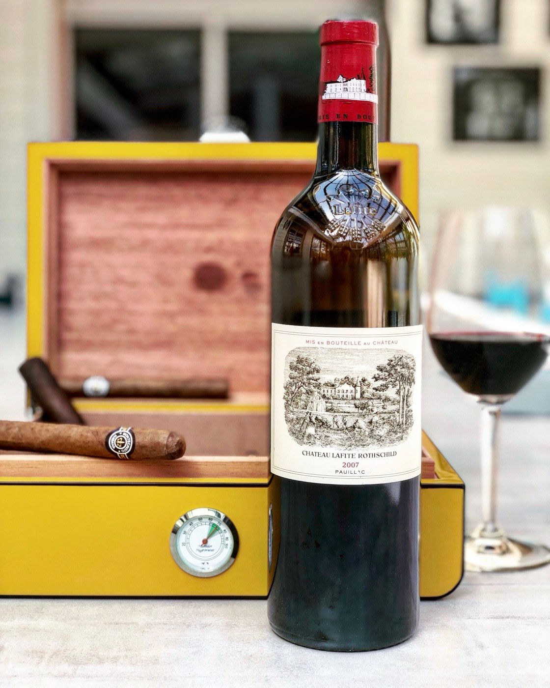 A prestigious bottle of Bordeaux next to a cigar box
