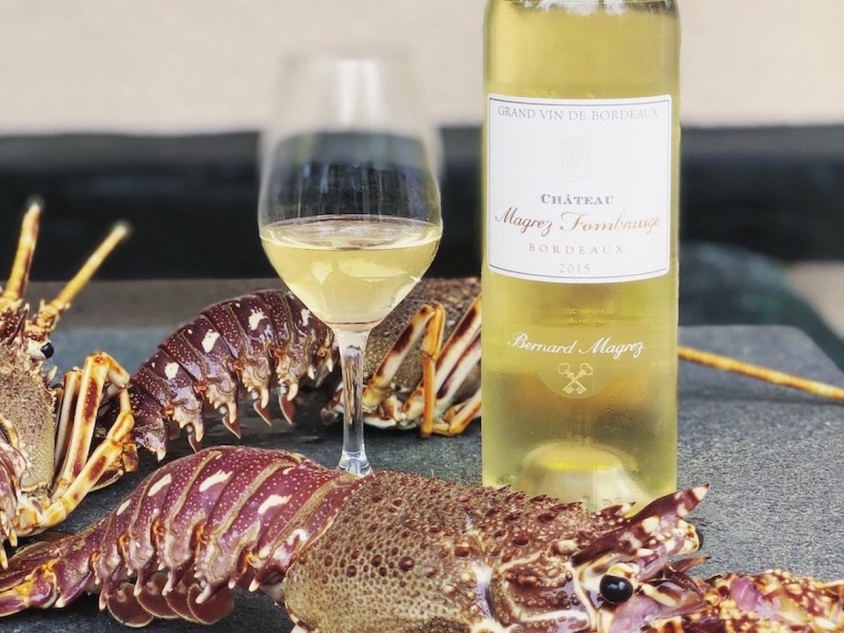 A glass of white wine and a bottle next to a seafood platter