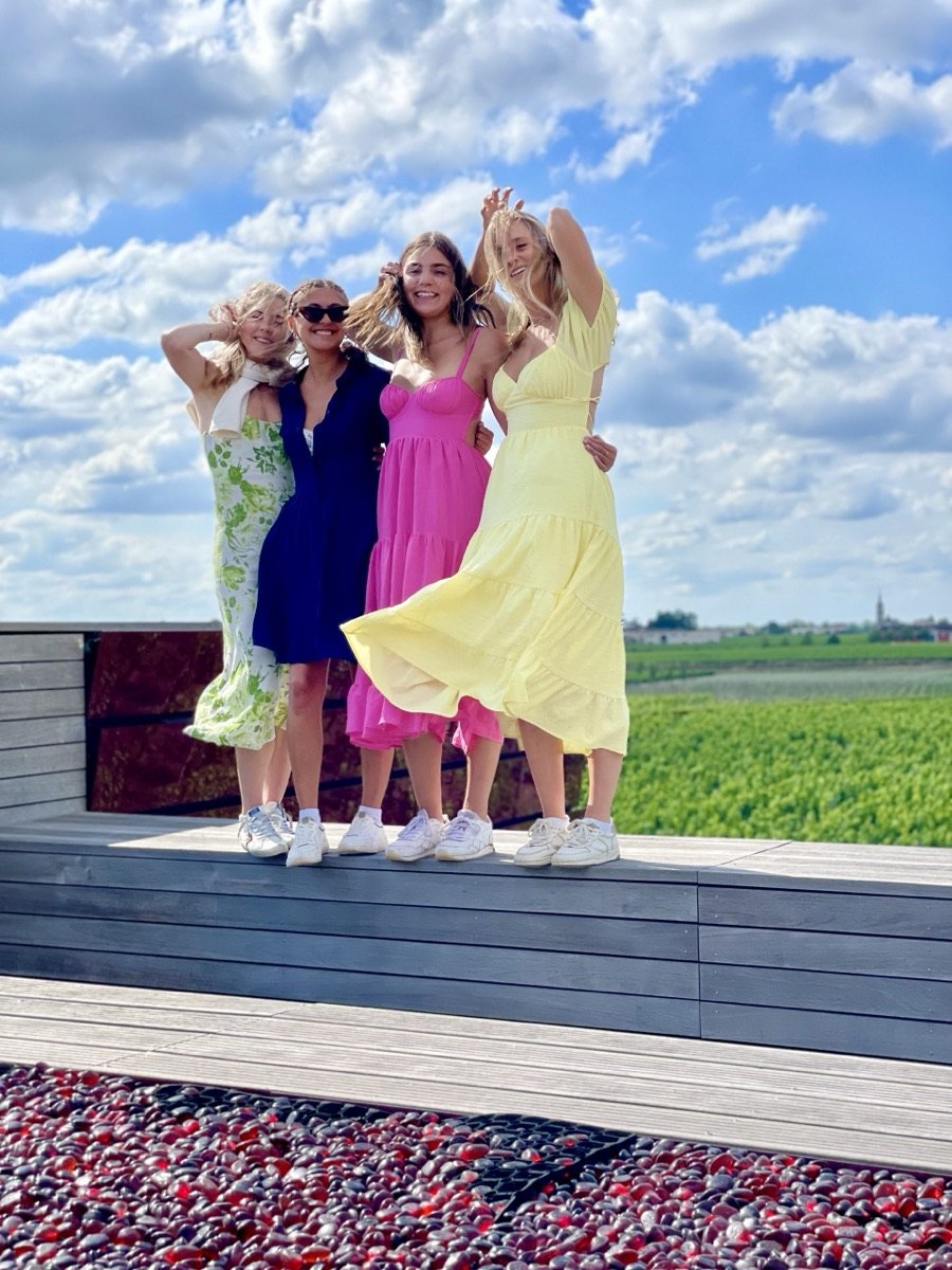Four friends in summer dresses posing in a vineyard