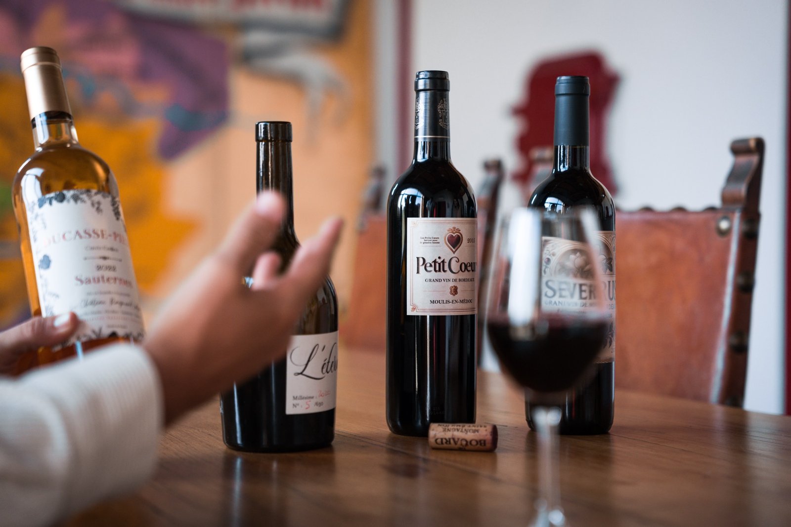 A hand pointing at bottles of great Bordeaux wines during a tasting