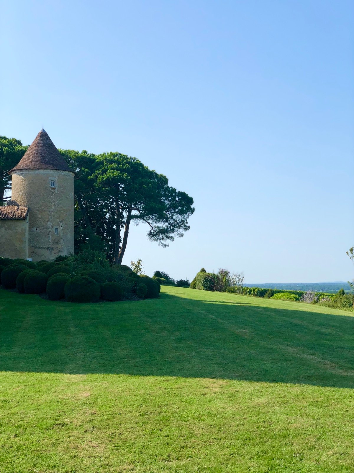 The tower of a Sauternes château above its lawn, under a summer sky