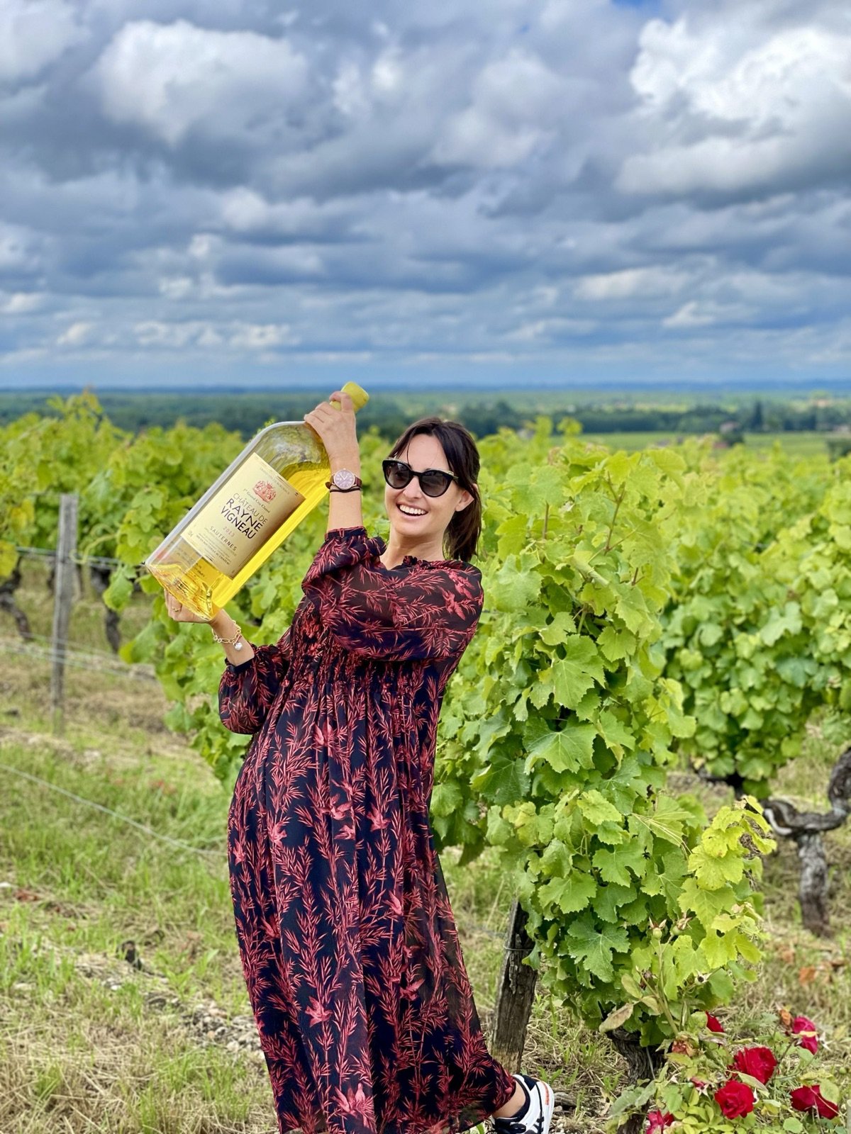 Holding a large bottle of Sauternes among the vines