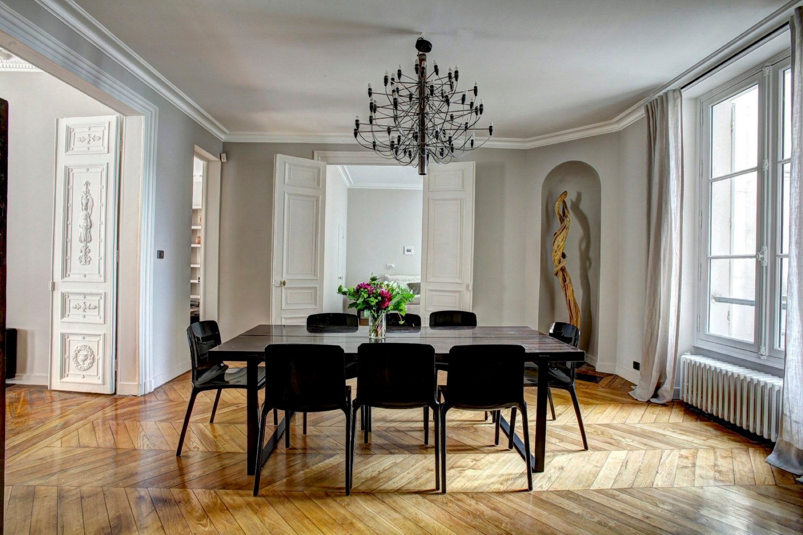 An elegant dining room with a chandelier and herringbone parquet