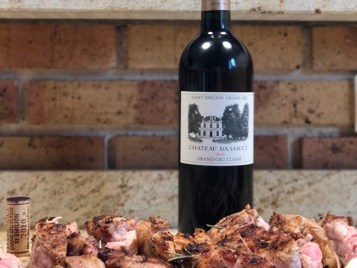A bottle of Château Dassault on a brick wall