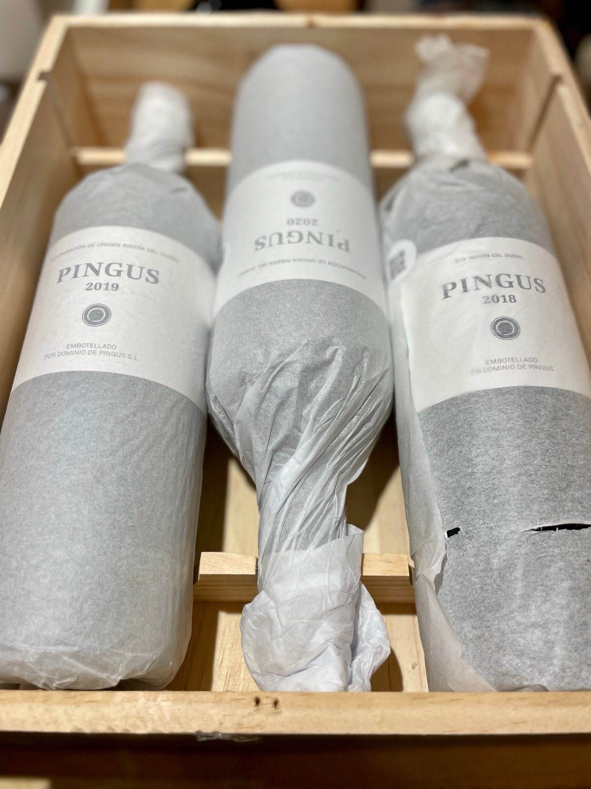 Bottles wrapped in tissue paper in an open wooden case