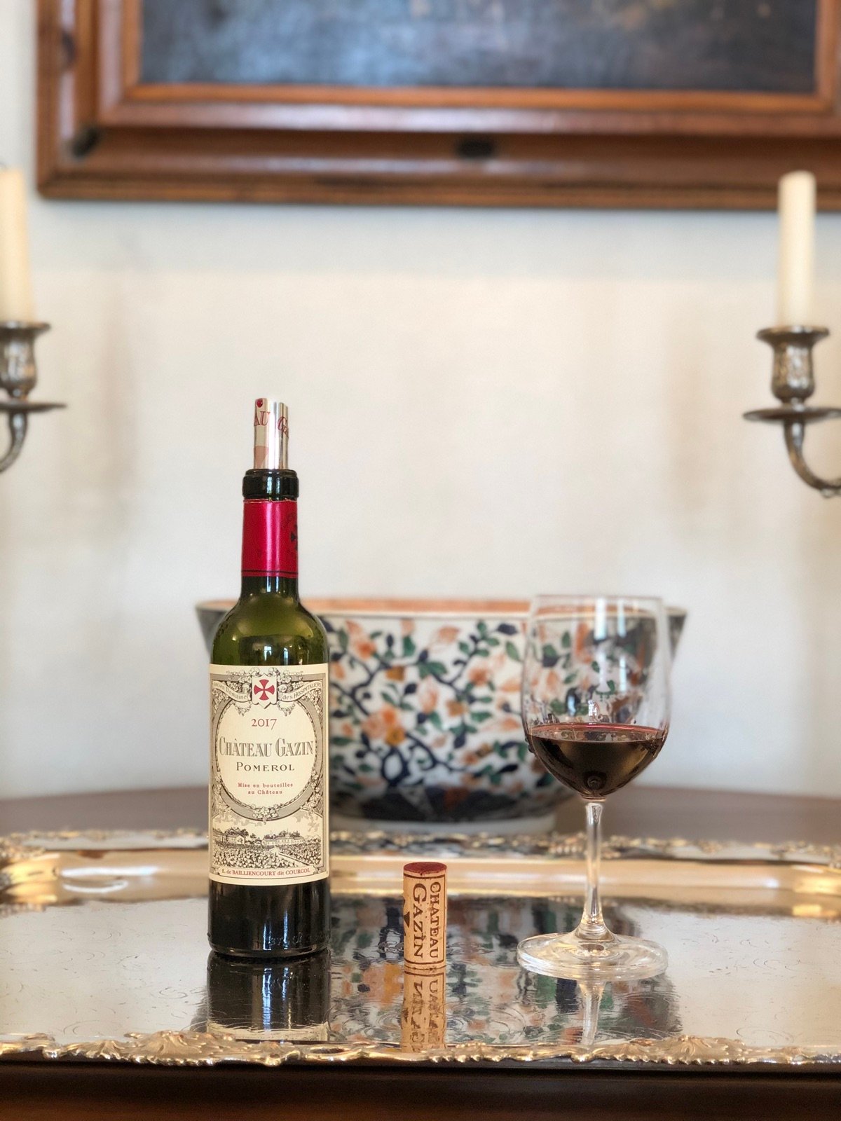 A bottle of Château Gazin and a glass of wine on a silver tray, by candlelight