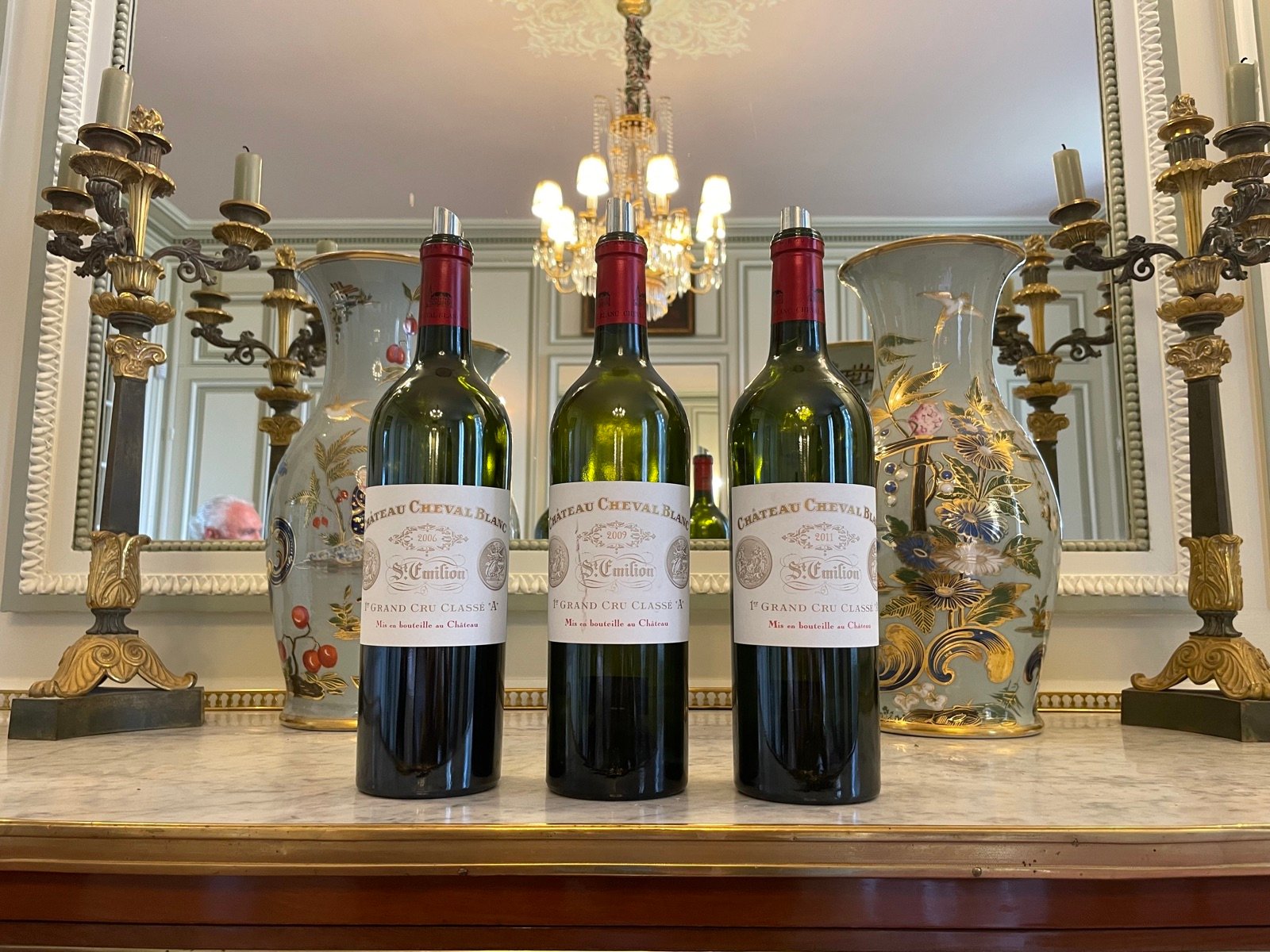 Three bottles of a great Bordeaux under a chandelier